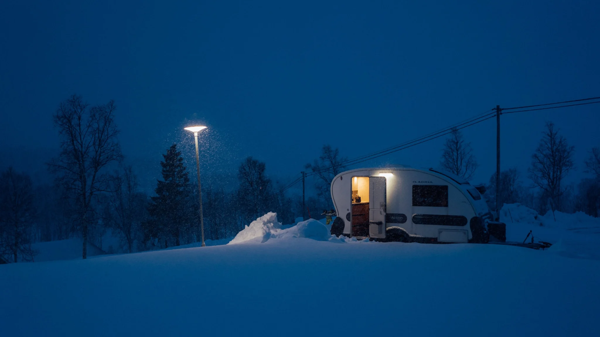 Vuokrattava asuntovaunu öisessä ja lumisessa Lapin maisemassa Rovaniemellä.