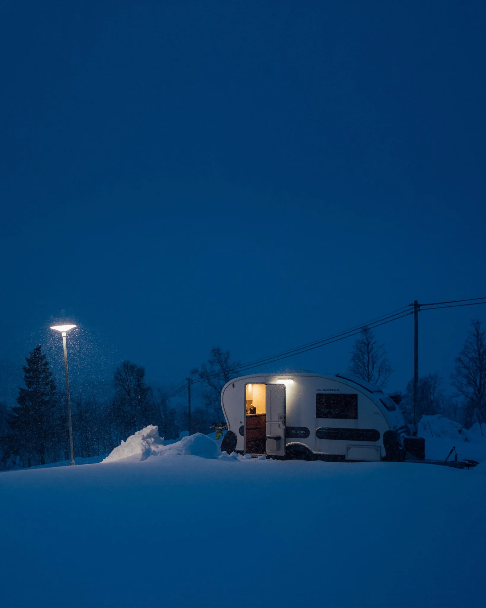 Vuokrattava asuntovaunu öisessä ja lumisessa Lapin maisemassa Rovaniemellä.
